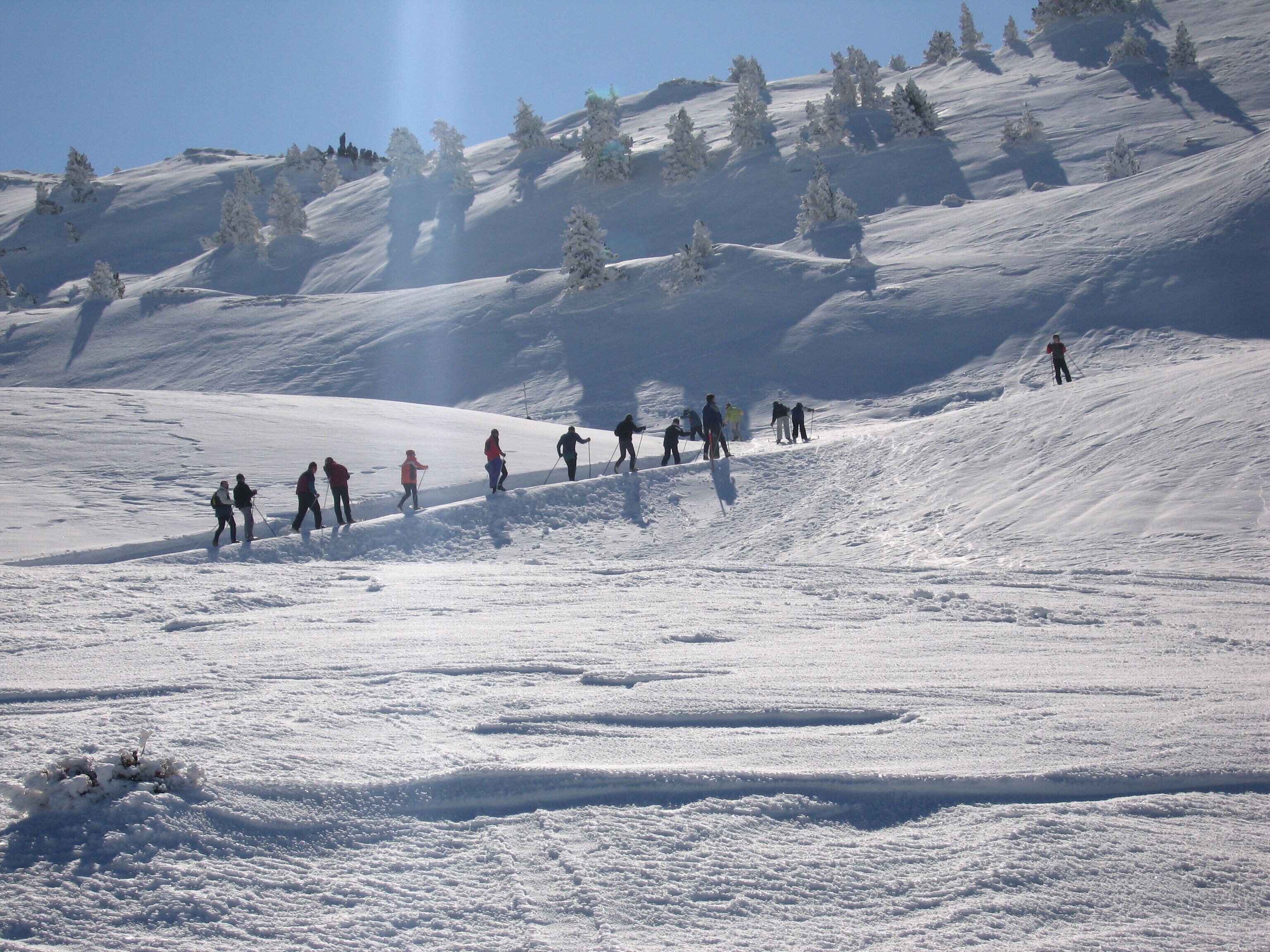 Een besneeuwde helling met skiërs die naar beneden gaan.