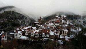 Un poble d'arquitectura tradicional, envoltat per turons nevats i boscos densos.