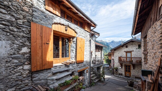 Ein Steinhaus mit Holzhörnern, einem Balkon und Blick auf die Berge.
