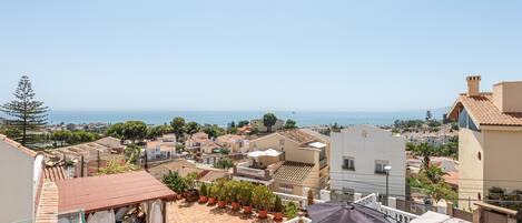 Eine Dachterrasse mit Pool, Sitzgelegenheiten im Freien und Blick auf das Meer und die umliegenden Gebäude.