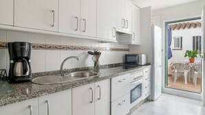 Una cocina moderna con armarios blancos, encimera de granito, cafetera, microondas y pileta.