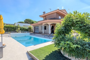 A residential property with a swimming pool, a two-story house, and a well-maintained garden.