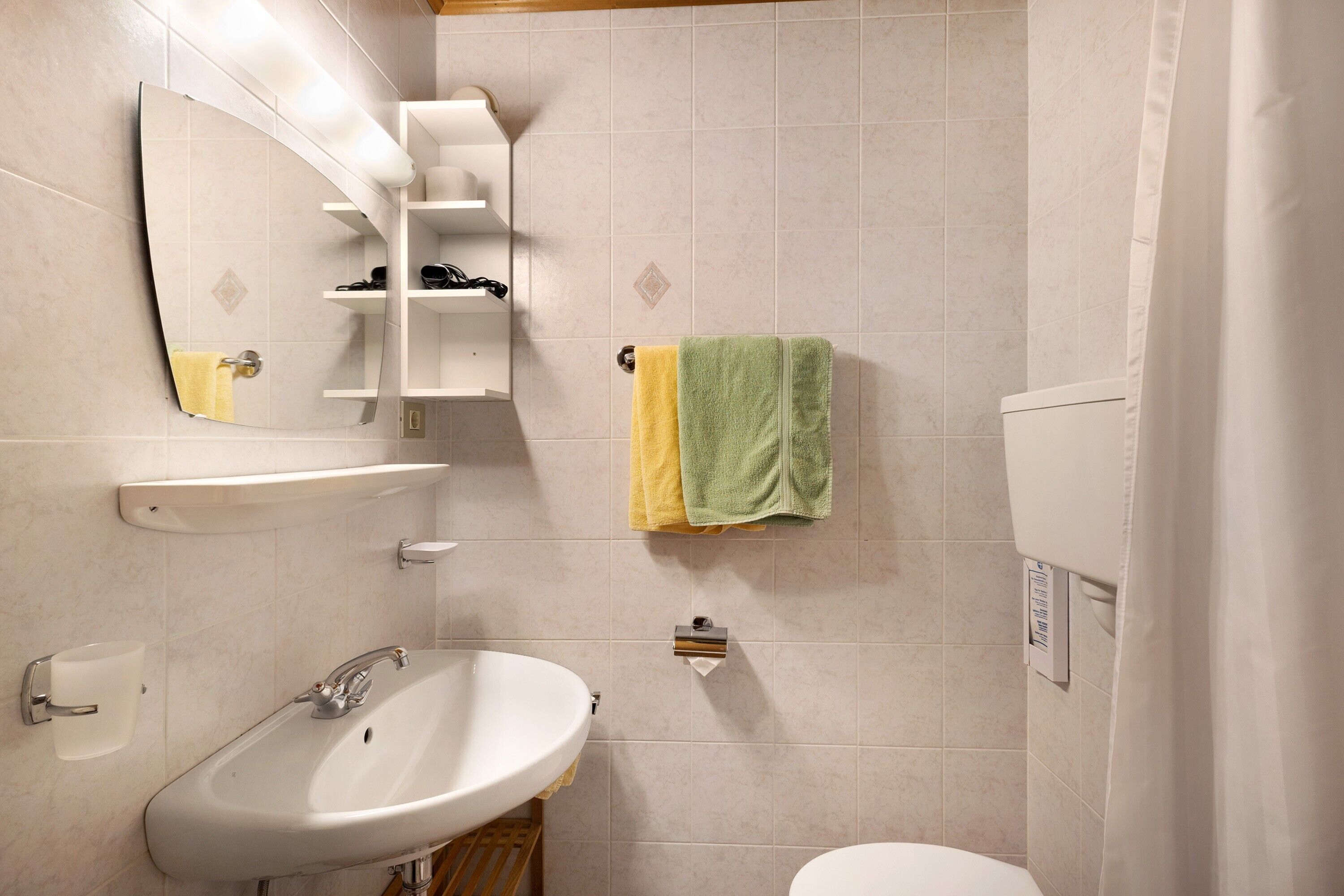 Une salle de bain équipée d’un lavabo, d’un miroir, d’un porte-serviettes et de toilettes.