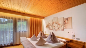 Un dormitorio con techo de madera, una cama grande con almohadas, una mesita de noche y una lámpara de pared.