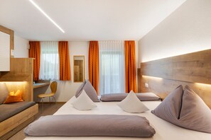 A hotel room with a bed, a desk, a chair, and a wooden headboard.