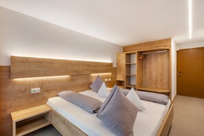 Un dormitorio con cabecera de madera, una cama con almohadas, un armario de madera y un pequeño banco.