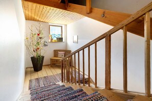 Eine Holztreppe mit Handlauf, einem Blumentopf, einer Bank und einem Fenster mit Aussicht.