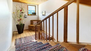 Un escalier en bois donnant sur une fenêtre, avec une plante en pot et un tapis.