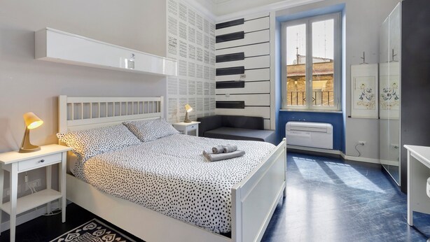 Ein Schlafzimmer mit Bett, Nachttischen, Heizkörper, Fenster und Kleiderschrank.