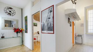 Ein Flur mit weißer Backsteinwand, einem Spiegel, einer Uhr und einem gerahmten Bild von einem Riesenrad.