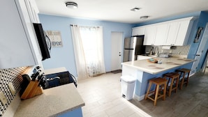 A modern kitchen with a central island, white cabinets, and a blue accent wall. - Relaxing Beach Home Only 3 Miles From Beach! (Fort Pierce)
