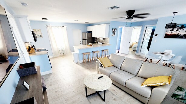 A spacious living room with a grey sofa, a round coffee table, and a TV. - Relaxing Beach Home Only 3 Miles From Beach! (Fort Pierce)