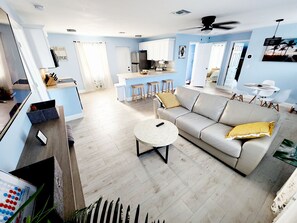 A spacious living room with a grey sofa, a round coffee table, and a TV.