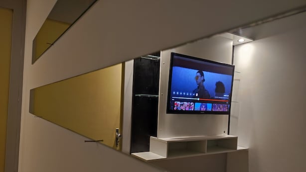 A modern interior with a mounted television displaying a video. - Apartamento Prime Central (Curitiba)