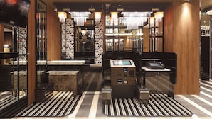 Un moderno vestíbulo de hotel con mostrador de recepción, quioscos de registro y vista al área de bar.