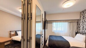Habitación de hotel con dos camas, un escritorio y un espejo.