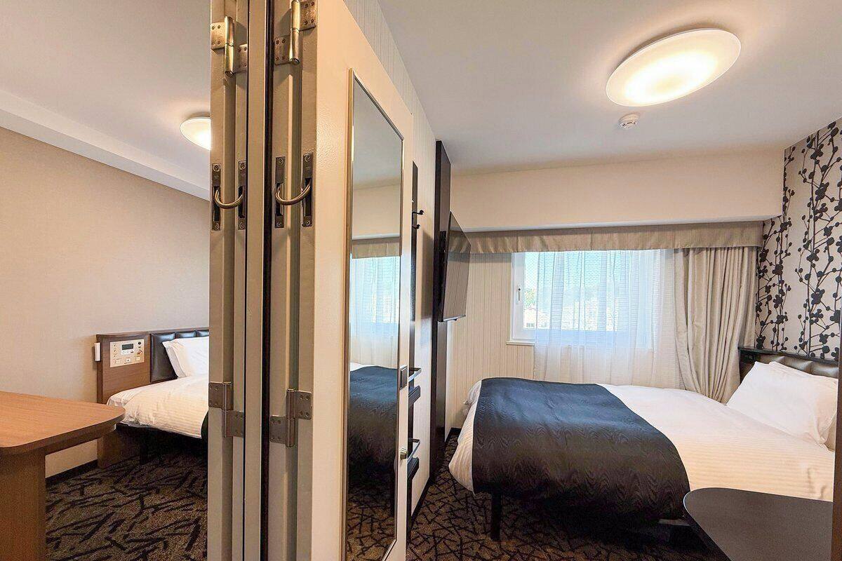Ein Hotelzimmer mit zwei Betten, einem Schreibtisch und einem Spiegel.