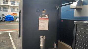 A black metal structure with a sign indicating a smoking area, a water bottle, and a metal bollard.