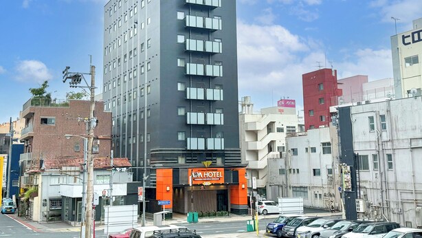 Un hotel de varios pisos con un letrero llamativo ADA HOTEL, que presenta un diseño moderno con balcones y techo plano.
