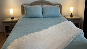 Una cama con edredón azul y blanco, dos lámparas de noche y un adorno decorativo sobre la cama.