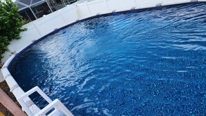 A swimming pool with a white deck and a wooden deck chair.