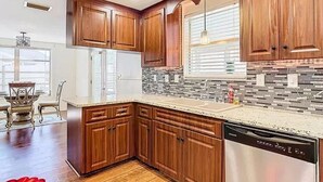 A modern kitchen with wooden cabinets, a stainless steel dishwasher, and a tiled backsplash.