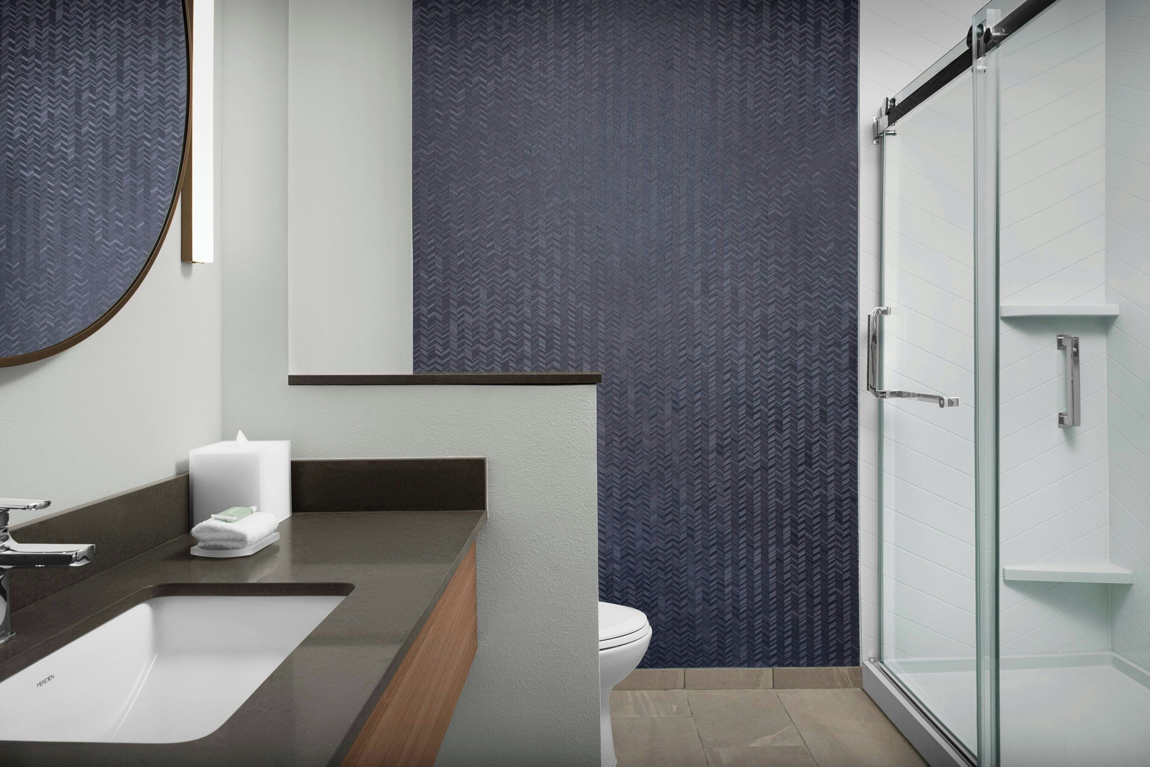 Un baño moderno con un espejo grande, un lavabo, un inodoro y una cabina de ducha de vidrio.