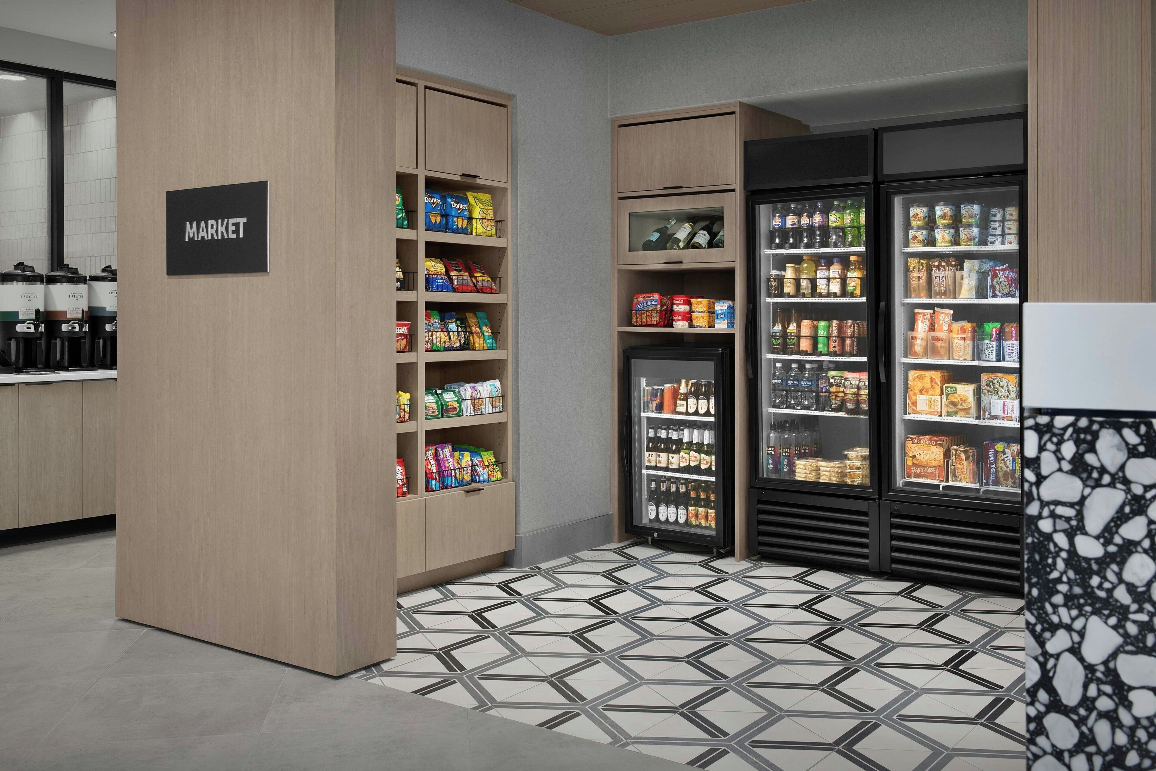 A modern market area with wooden shelving stocked with snacks, beverages, and other food items.