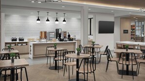 Un café moderno con mesas redondas y sillas negras, un salpicadero de azulejos blancos e iluminación colgante.