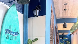 Un pasillo con una tabla de surf, plantas en macetas y suelo de baldosas.
