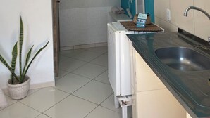 Una cocina con un lavamanos, un refrigerador blanco, una pared de acento color turquesa y un adorno colgante.