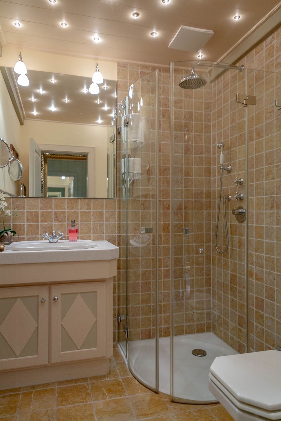 Un baño moderno con cabina de ducha de vidrio, tocador con lavamanos y retrete.