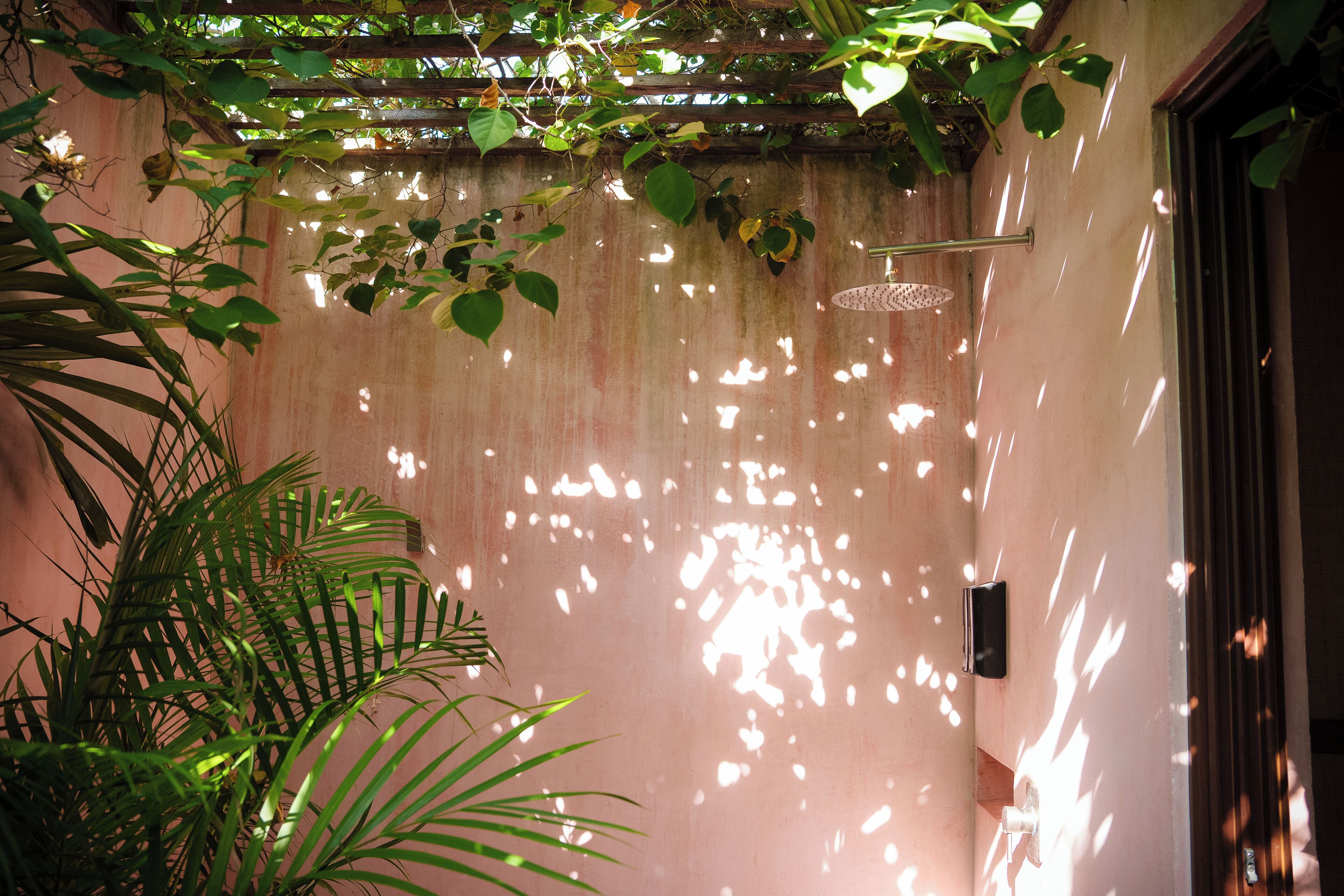 Une pièce avec un mur rose, un luminaire suspendu et une porte dotée d’un panneau en verre.