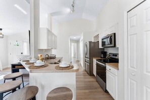 A modern kitchen with white cabinetry, a central island with seating, and stainless steel appliances.