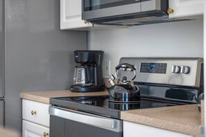 A kitchen with a stove, a kettle, and a coffee maker.