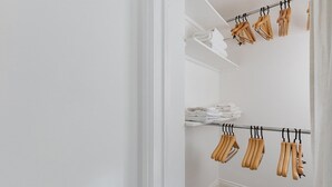 Un placard avec des cintres en bois et des serviettes pliées rangées sur des étagères.