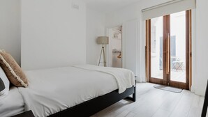 Une chambre avec un lit, une lampe sur pied et une porte-fenêtre coulissante donnant sur un espace extérieur.