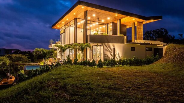 A modern house with a large deck, a swimming pool, and a well-maintained garden.