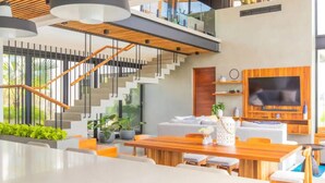 A modern living room with a staircase, wooden ceiling, and a large flat-screen TV.