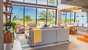 A modern living room with a large gray sofa, wooden coffee table, and a view of the ocean.