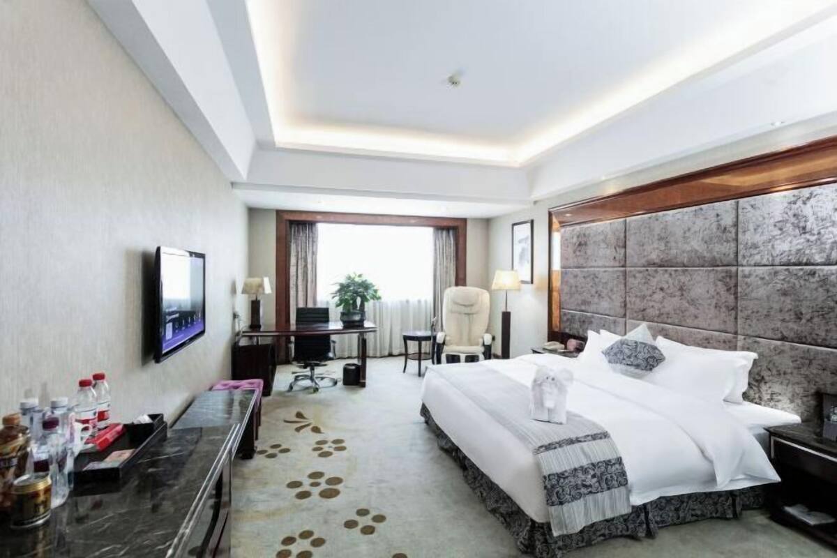 Une chambre d’hôtel équipée d’un lit, d’un bureau, d’une chaise, d’une télévision et offrant une vue sur l’extérieur.