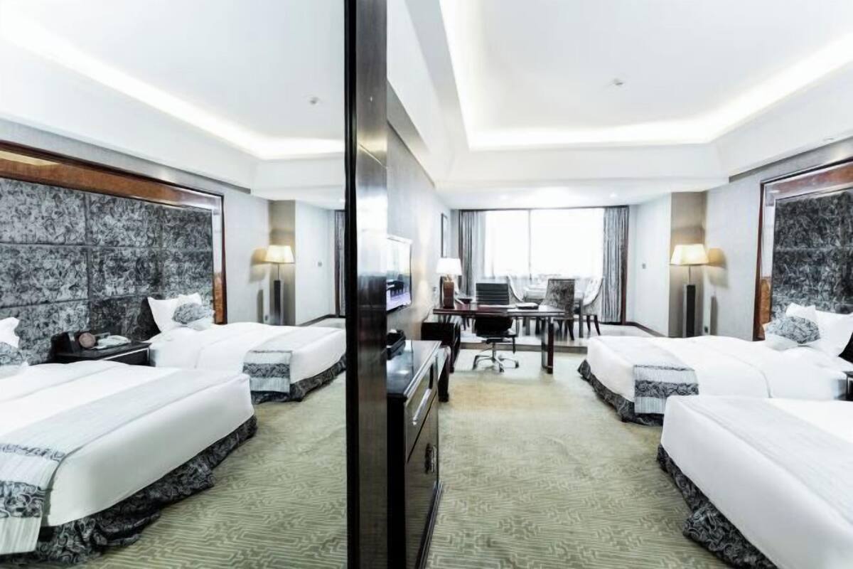 Une chambre d’hôtel avec deux lits, un bureau et une chaise.