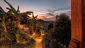 Un sendero de jardín que lleva a una estructura de madera con escalones y abundante vegetación.