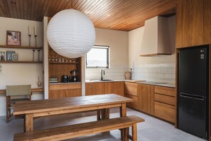 A modern kitchen with wooden cabinets, a black refrigerator, and a wooden dining table with benches. - Surf Loft 4 by Alfred in Bali (Cemagi)