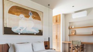 Une chambre à coucher avec un grand lit, un ventilateur de plafond, un bureau en bois et une chaise.