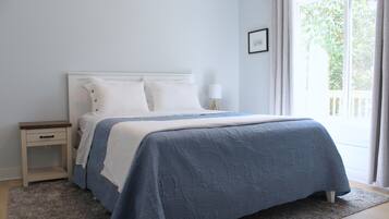 A bedroom with a bed, nightstand, and window.