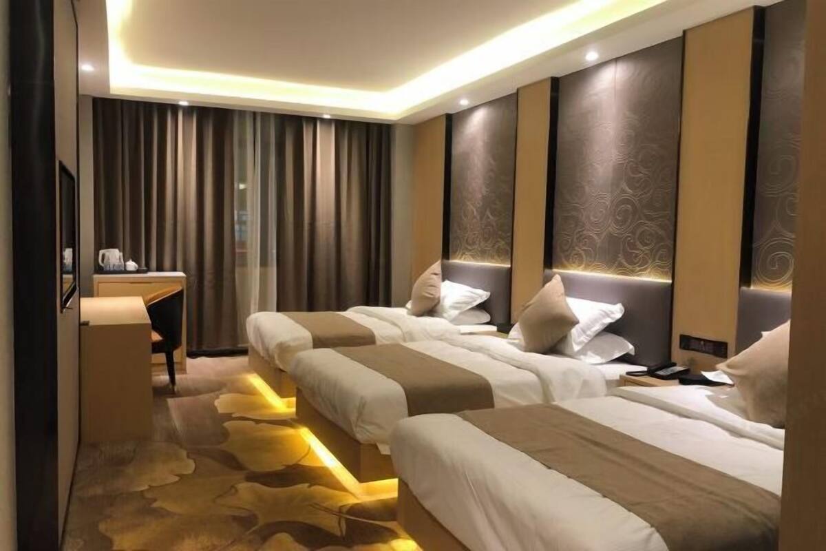Ett hotellrum med två sängar, ett skrivbord och en spegel.