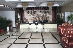Un área de recepción con mostrador de registro, un sofá de cuero rojo y piso de baldosas.