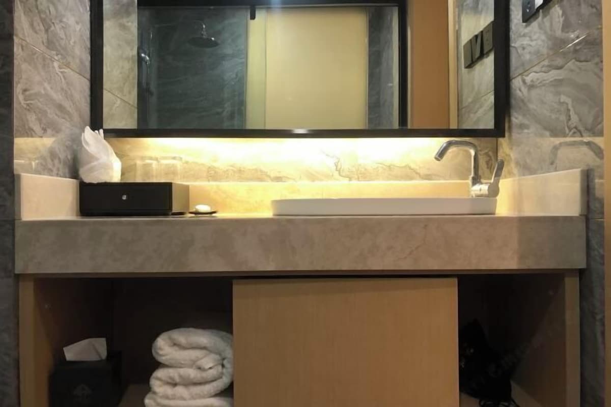 Un baño con encimera de mármol, un lavabo, un espejo y un perchero para toallas.