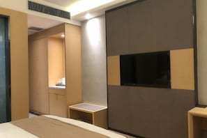 Una habitación de hotel moderna con una cama, un televisor montado en la pared y una mesita de noche.